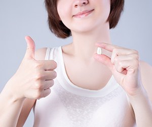 woman holding her tooth and giving a thumbs up