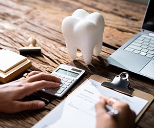 person calculating the cost with a tooth on the desk