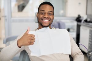 man smiling and giving a thumbs up in the dental chair