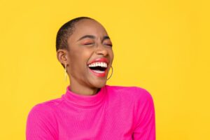 smiling woman wearing pink in front of a yellow background