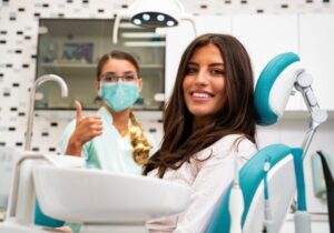 smiling patient with the dentist giving a thumbs up beside her